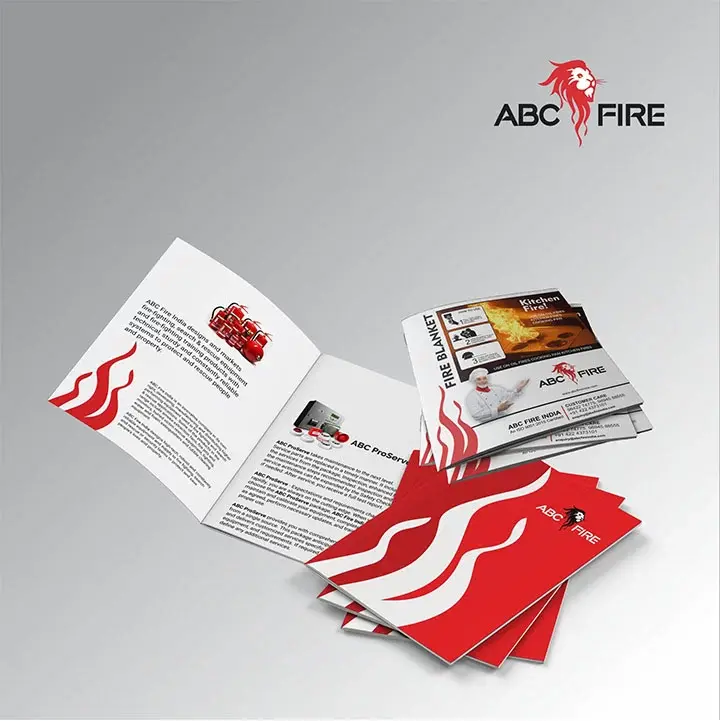 ABC Fire - product catalogue bifold open showing fire blanket ad and ABC ProServe product pages, business cards fanned in foreground