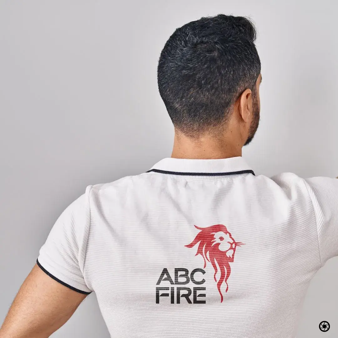 ABC Fire - staff polo viewed from the back, lion mark and ABC FIRE wordmark printed between the shoulder blades