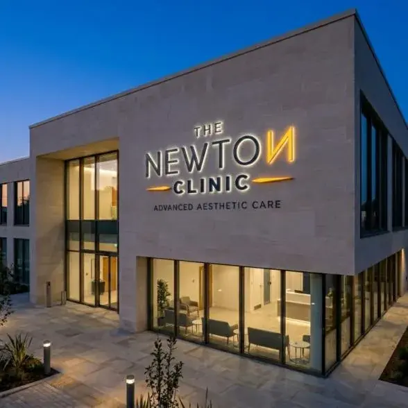 The Newton Clinic illuminated logo on the building facade at dusk